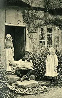 Man reading newspaper outside his cottage, Shropshire