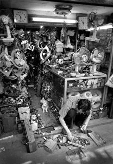 Images Dated 8th August 2019: Man squats on floor of his streetside workshop, Hong Kong