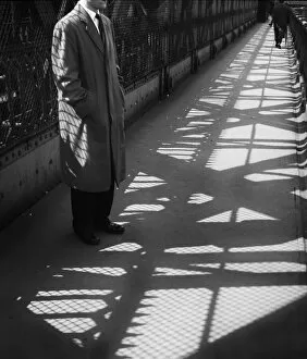 Man standing on bridge in light and shade