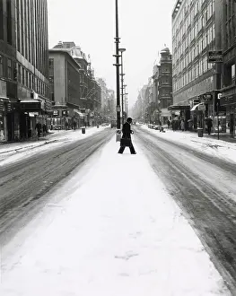 Shoppers Prints: A man in a suit with a briefcase crosses a snowy Oxford Street Date: 1960s