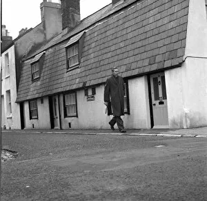 Past Gallery: Man walking past Tom Thumb cottages, Eastbourne