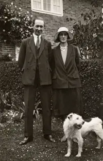 Man and woman with a terrier dog in a garden