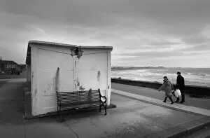 Images Dated 27th August 2019: Man and woman walk along the sea front in high winds, Troon