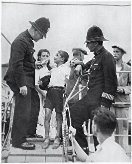 Gang Collection: Two members of Gibraltar's police force questioning a Spanish boy on the gang-way of a refugee