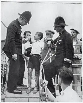 Two members of Gibraltar's police force questioning a Spanish boy on the gang-way of a refugee boat, August 1936. The Spanish Civil War, which started in the summer of 1936, meant that thousands of Spaniards became refugees