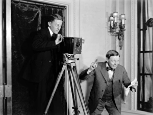 Two men making a film using a movie camera indoors in Americ