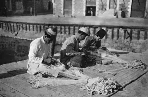 Three men repairing fishing nets, Holy Land