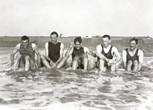 Five men sitting in the sea in bathing suits