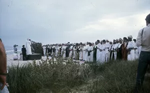 Men stand praying by the beach in Oman