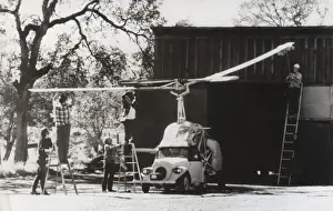 Men Standing on Ladders Attaching the Rotors Onto a Heli?