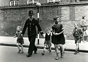 Images Dated 16th February 2011: Metropolitan Police officer and children crossing road