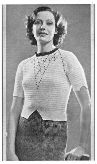 Shaped Collection: Model wearing a knitted sweater in white Tricoton cotton with shaped sleeve cuffs. Date: 1935