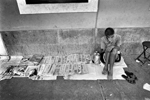A newpaper seller sits on the pavement in a street in Canton A newpaper seller sits on the pavement in a street in Canton