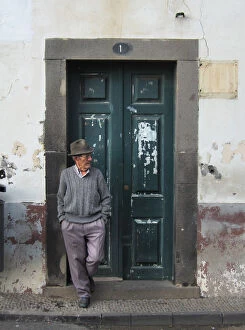 Old man in trilby leans against a doorway, Funchal, Maderia