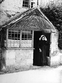 Old woman at cottage porch, 1890s