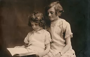 Affection Collection: Older girl helps her younger sister read a book