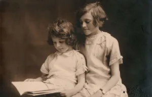 Affectionate Gallery: Older girl helps her younger sister read a book
