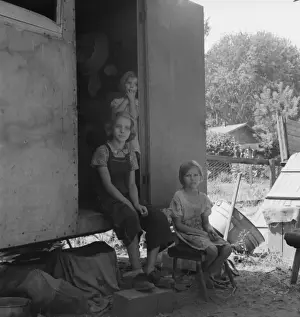 The oldest girl seated in the doorway of the house trailer c
