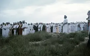 Omani elders stand with heads bowed in Oman