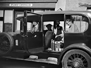 Four people in a car outside a Post Office