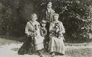 Four people and three dogs in a garden