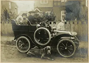 People in an early car with two dogs