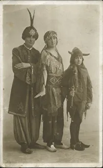 Three people in fancy dress; two adults in exotic Arabian Nights style outfits Three people in fancy dress; two adults in exotic Arabian Nights style outfits