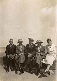Images Dated 31st March 2017: Five people sitting on a wall at the seaside