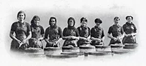 Photograph showing a group of Scottish women standing over the barrels that are being