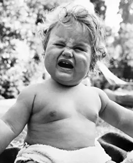 Plump baby crying in a garden