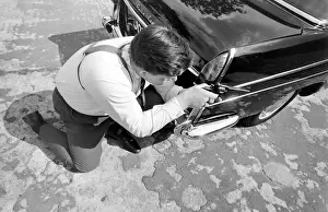 Policeman aiming his gun round the side of a car during training at the Police Gun School