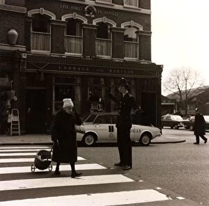 Images Dated 17th February 2011: Policeman helping an old lady cross the road