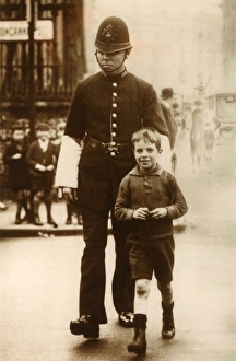 Images Dated 16th February 2011: Policeman helping a young boy cross the road