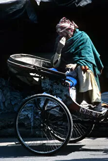 A ragged driver sits on his cycle rickshaw, India