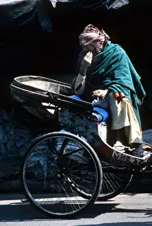 Scruffy Prints: A ragged driver sits on his cycle rickshaw, India