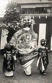 Rear view of a Japanese Actress in remarkably elaborate costume with two children Date Rear view of a Japanese Actress in remarkably elaborate costume with two children Date