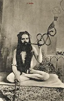A Sadhu smoking a remarkable pipe, India