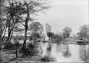 A scene of a river with small boats in the middle distance