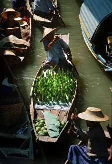 Afloat Gallery: Seller paddles his boat into Damnoen Saduak floating market