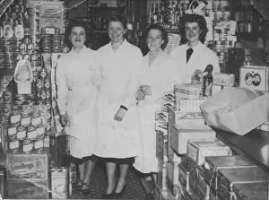 Four shop workers line up for a photograph in a well-stocked grocery store Four shop workers line up for a photograph in a well-stocked grocery store