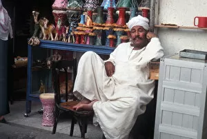 Images Dated 8th August 2019: Shopkeeper lounges outside his souvenir shop, Cairo, Egypt
