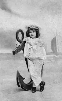 Small boy in a sailor suit poses with a large anchor