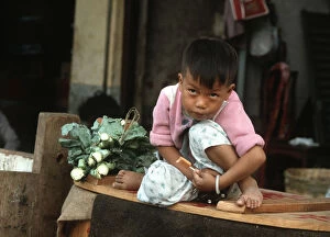 Images Dated 8th August 2019: A small boy sits on his mothers vegetable stall, Hong Kong