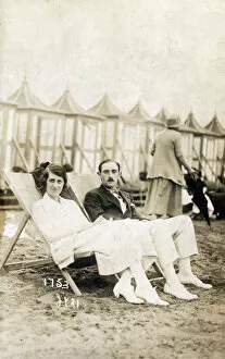 Images Dated 29th April 2020: Smart young couple sat on the beach in deckchairs