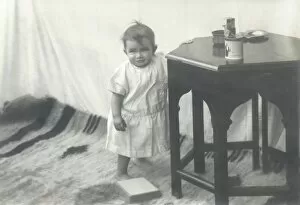 Smiling toddler leaning against a table