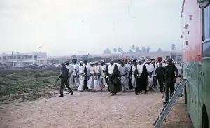 Soldiers with Omani elders walking in the sand. in Oman