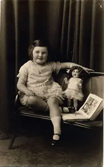 Dolls Prints: Studio photograph of a little girl pictured with a doll and picture book