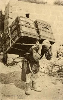 Syrian Porter carries two enormous trunks on his back