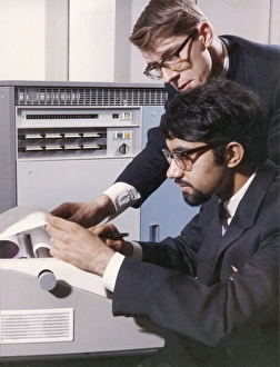 Two technicians check a computer printout Two technicians check a computer printout