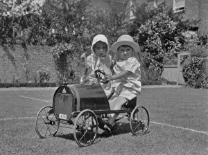 Two toddlers with toy car in a garden